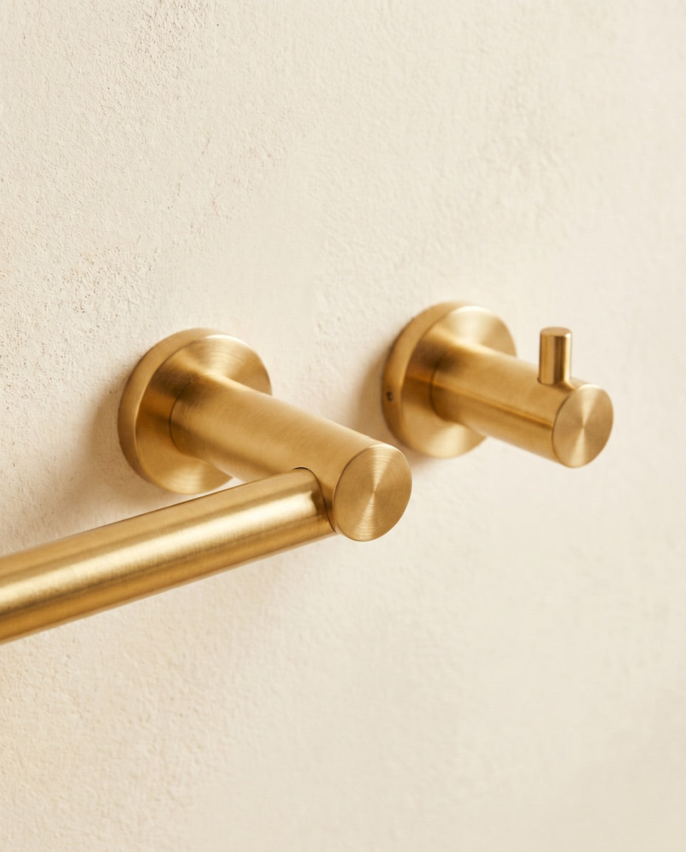 A detail of a coordinated brushed-gold towel bar and robe hook hardware set.