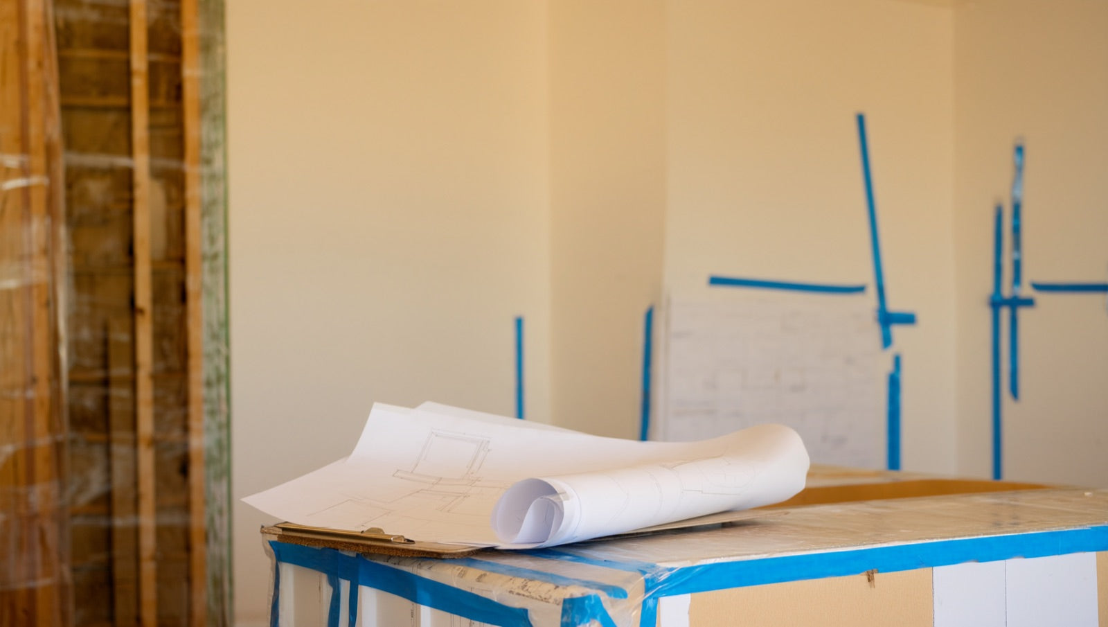Kitchen renovation plans and permit paperwork laid out on a plywood counter during rough-in