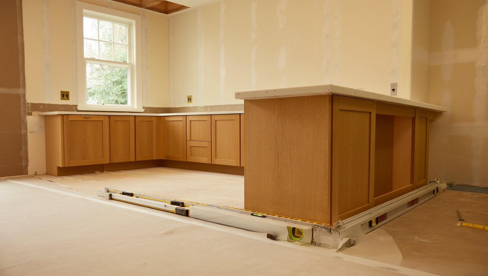 Kitchen mid-remodel: installed cabinets awaiting countertop templating, floor protection still down