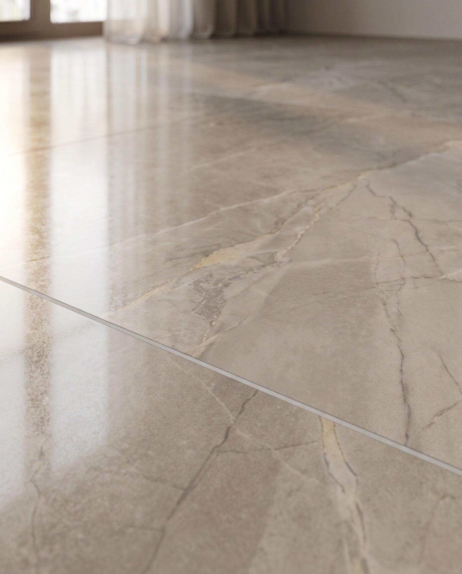 A polished detail of large-format marble-look porcelain floor tile with soft grey and pale-gold veining.