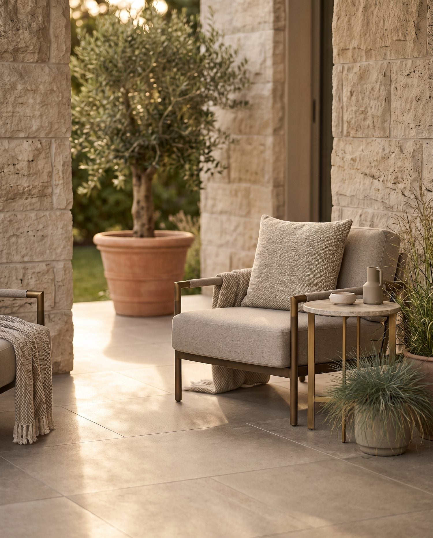 Styled backyard patio corner vignette with 2cm porcelain pavers, a bronze-accented lounge chair, and muted greenery at golden hour