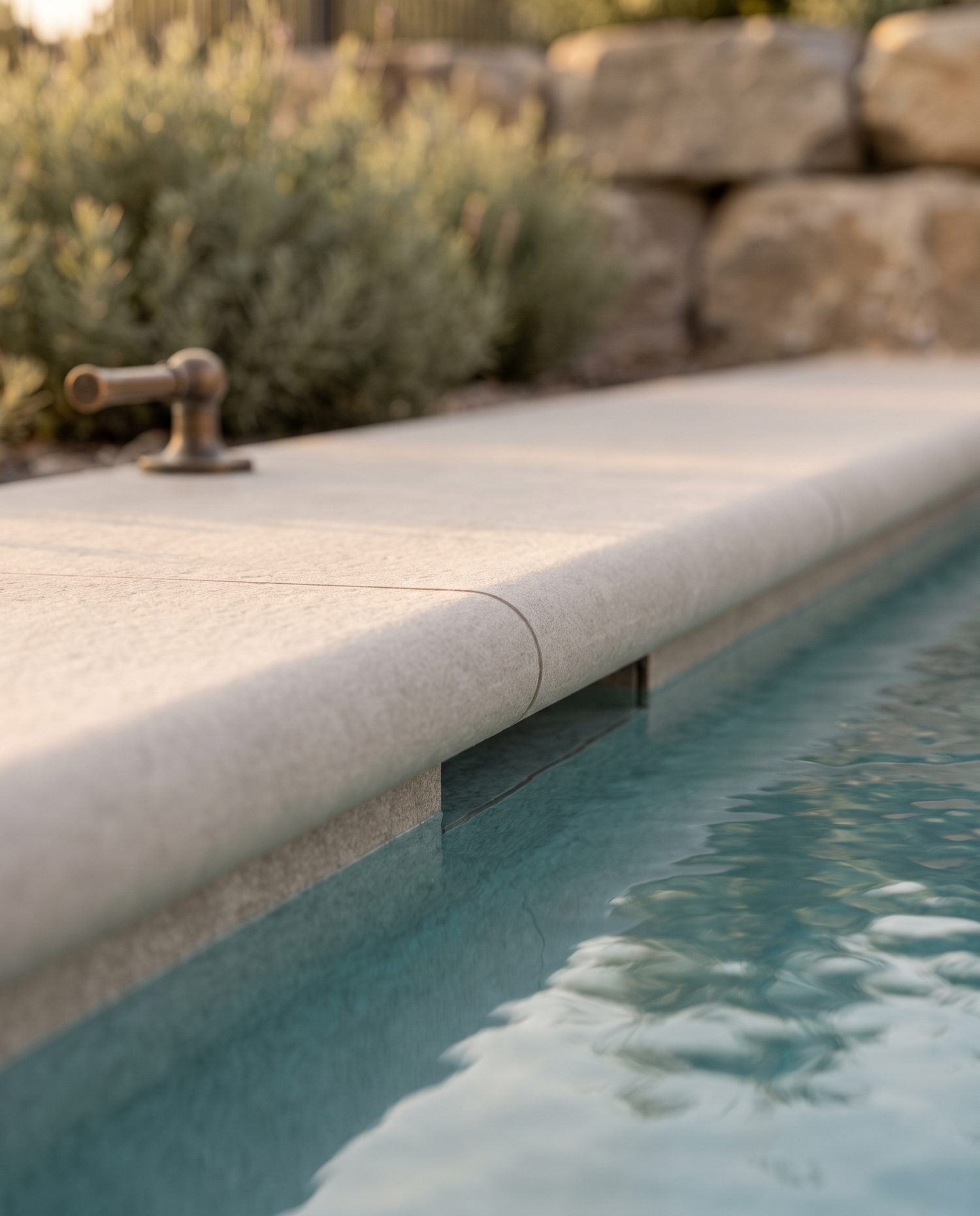 Tight detail of a bullnose porcelain coping meeting a 2cm porcelain deck paver at a pool edge, showing the rounded profile and textured surface