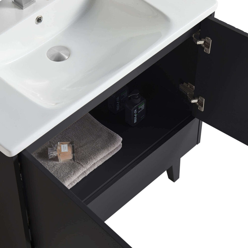 A Venezian 30 inch Bathroom Vanity With Sink in black is shown with its cabinet door open, displaying a folded gray towel, a soap bar, and small toiletry bottles arranged on the shelf below the white sink.