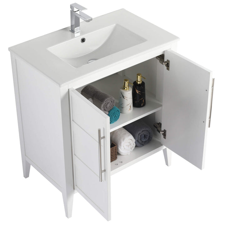 The Leafside 30 Inch Bathroom Vanity With Sink showcases a sleek rectangular sink and chrome faucet. Inside its cabinet doors, the shelves hold stacked towels, a decorative box, and two elegant bottles, blending style with functionality.