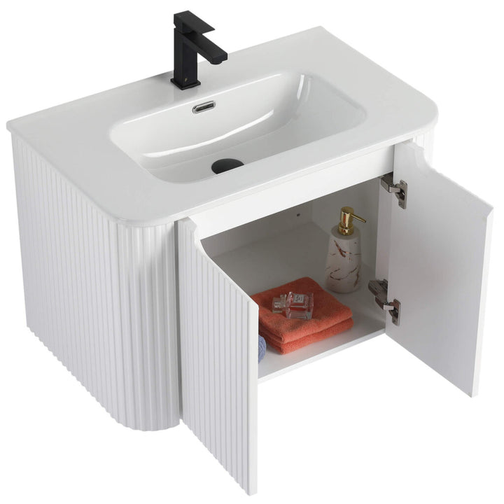 The Caskvalley 30 Inch Wall Mounted Bathroom Vanity With Sink showcases a white ribbed texture, a rectangular sink, and a black faucet. Open its cabinet doors to find an orange towel and liquid soap dispenser, blending style with functionality for your bathroom.