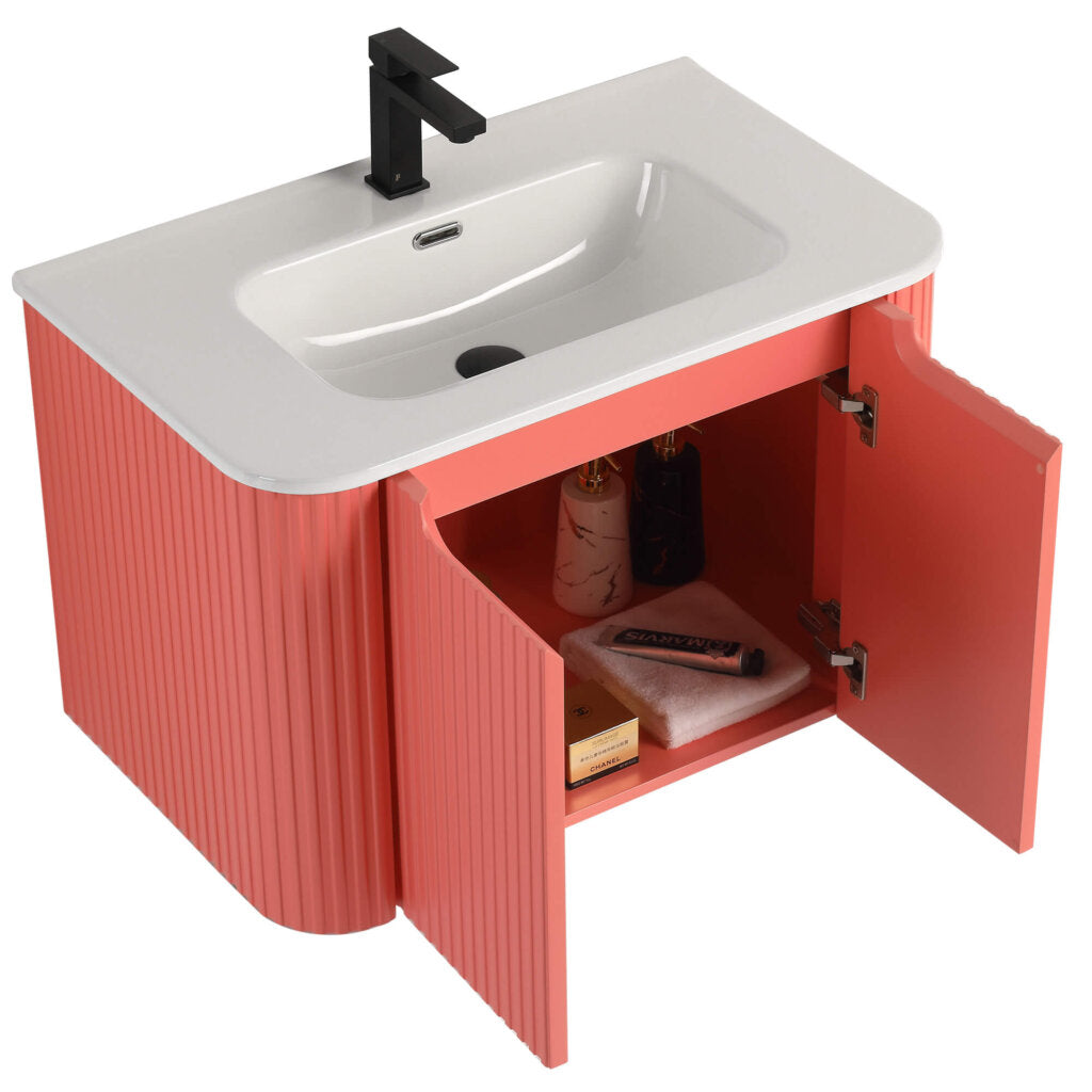 Discover the Caskvalley 30 Inch Wall Mounted Bathroom Vanity With Sink, marrying elegance and utility; a white sink paired with a black faucet sits on coral-textured cabinets, highlighted by open doors displaying neatly organized bottles and towels.