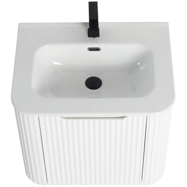 The Caskvalley 24 Inch Wall Mounted Bathroom Vanity features a ribbed cabinet with a white rectangular basin, a sleek black faucet, central drain, and overflow hole, offering a modern design that contrasts beautifully with the smooth sink surface.