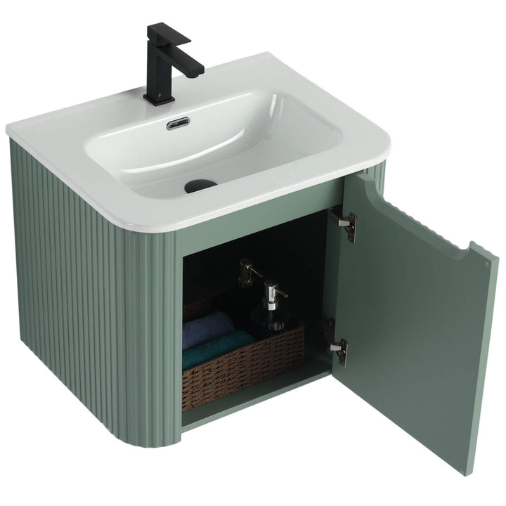 Unveil the Caskvalley 24 Inch Wall Mounted Bathroom Vanity With Sink. It features a modern white basin, sleek black faucet, and a green ridged wooden cabinet with an open door, showcasing a wicker basket containing toiletries and folded towels.