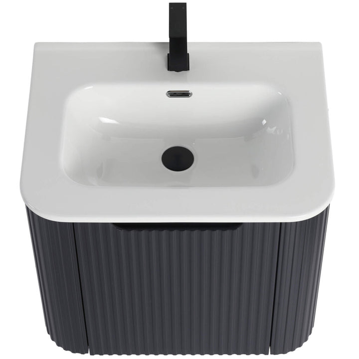 The Caskvalley 24 Inch Wall Mounted Bathroom Vanity With Sink boasts a modern white ceramic basin paired with a single black faucet atop a dark ribbed cabinet, featuring an overflow hole and central drain for seamless style and functionality.