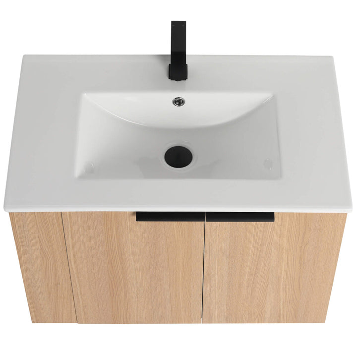 The Elmridge 30 Inch Wall Mounted Bathroom Vanity With Sink features a rectangular white ceramic sink with a black faucet on a light wood base. This modern design includes a central drain and faucet hole, providing an elegant and functional bathroom upgrade.