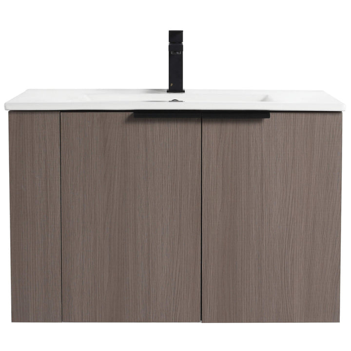 The Elmridge 30 Wall Mounted Bathroom Vanity features a modern design with a wood-textured cabinet, two doors, and sleek black handle. Its integrated white countertop and minimalist black faucet enhance its contemporary aesthetic.