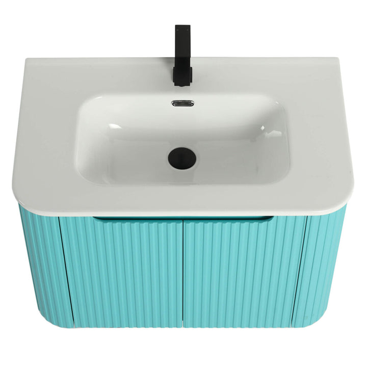 A top-down view of the Caskvalley 30 Inch Wall Mounted Bathroom Vanity With Sink highlights its modern aesthetic with a glossy white basin, sleek black faucet, and turquoise cabinet featuring a vertical ribbed texture. The vanity has two doors and is set against a plain white background.