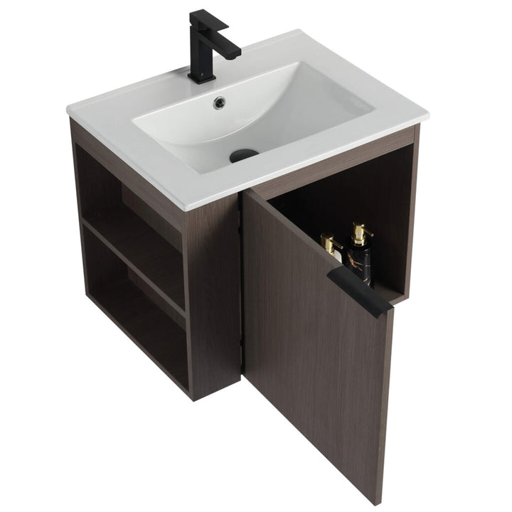 The Elmridge 24 Wall Mounted Bathroom Vanity With Sink features a modern design including a square white basin and sleek black faucet, complemented by a dark brown wooden cabinet with side shelving, an open door, and two visible bottles for easy storage.