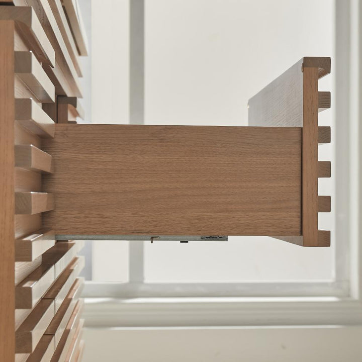 A close-up side view of a wooden drawer in the Linea 48 Inch Wall Mounted Bathroom Vanity, partially open to reveal its modern slatted design and dovetail joints, with sunlight streaming through a window in the background.