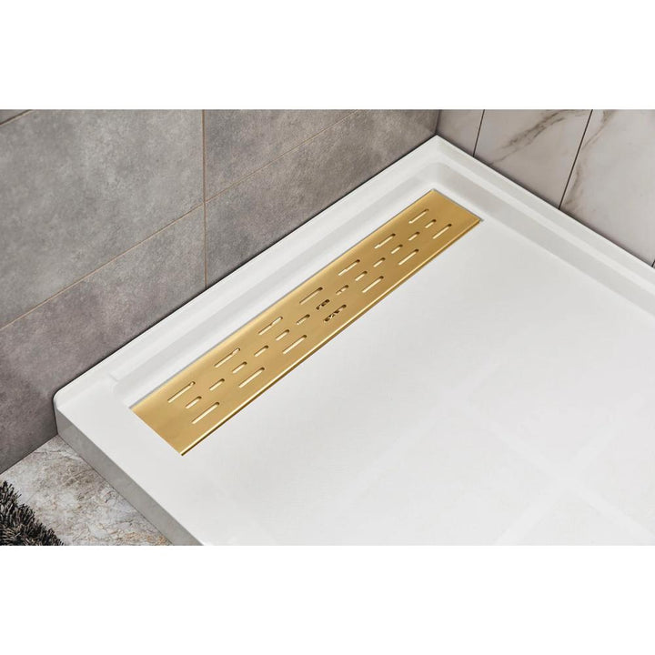 A modern shower floor featuring the Bhavana Single Threshold Shower Base with a rectangular white tray and gold linear drain cover, set against sleek gray and marble-patterned wall tiles.