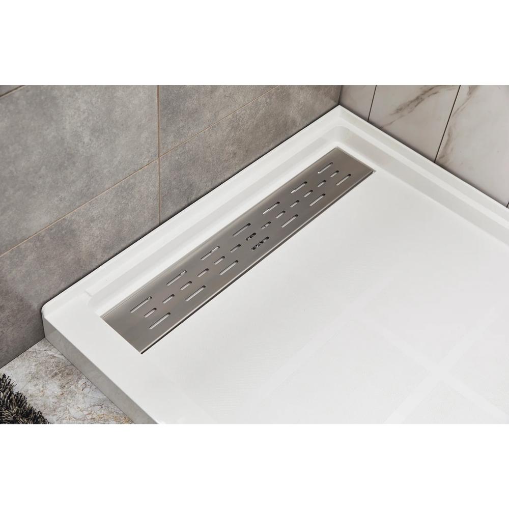 A close-up view of a modern shower floor with a white textured base and a rectangular stainless steel linear drain, surrounded by gray and marble-patterned tiles.
