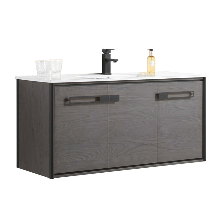 The Oakville 48 inch Modern Bathroom Vanity is wall-mounted with a dark wood finish, three cabinet doors, a white countertop, modern black faucet, two glasses, and a soap dispenser.