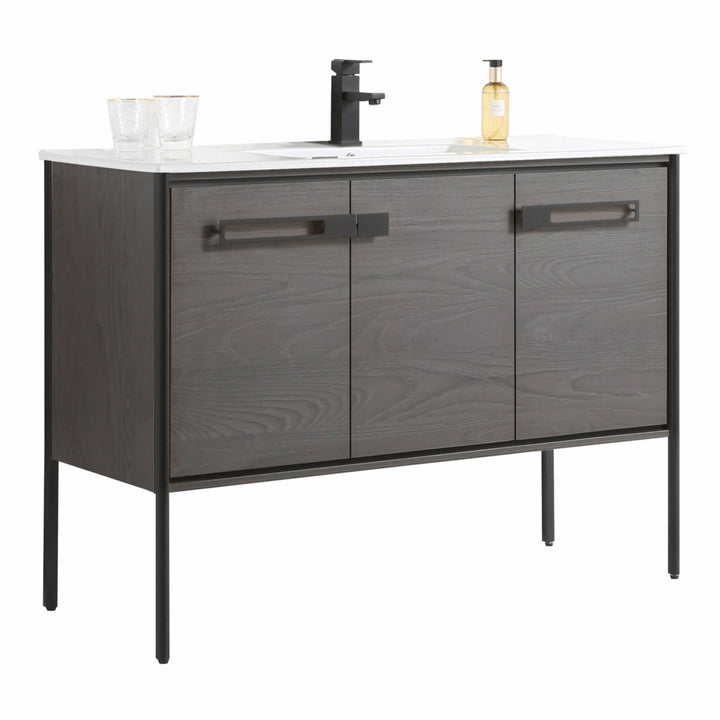 The Oakville 48 inch Modern Bathroom Vanity showcases a dark wood finish, three cabinet doors with black handles, white countertop, black faucet, two glasses, and a soap dispenser—perfect for contemporary bathrooms.