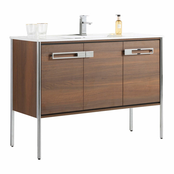 The Oakville 48 inch Modern Bathroom Vanity features a wood finish, metal legs, two spacious drawers, and a white countertop with faucet, two clear glasses, and a soap dispenser.