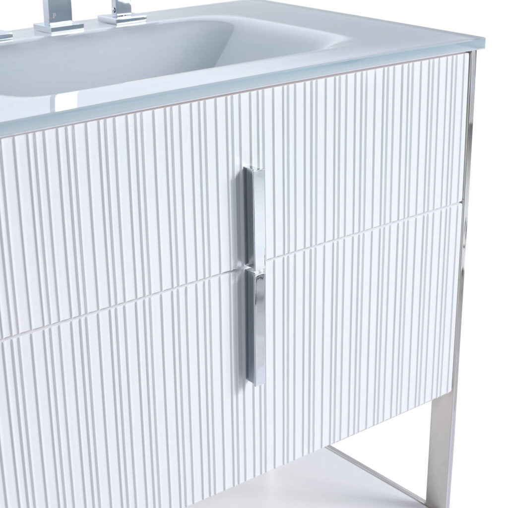 Close-up of a modern bathroom vanity with a white ribbed cabinet front, a sleek chrome handle, and a white sink on top. The vanity has a minimalist design with metal legs.