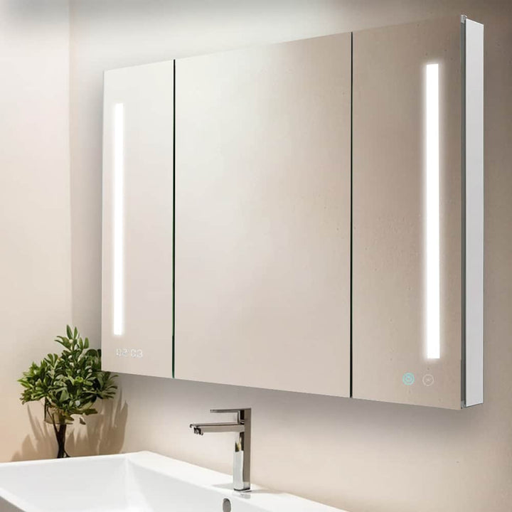 The Signature Royale 40 Inch x 36 Inch LED Lighted Mirror Medicine Cabinet features three mirrored doors, vertical LED light strips, a modern sink below, and a small green plant on the left side of the countertop.