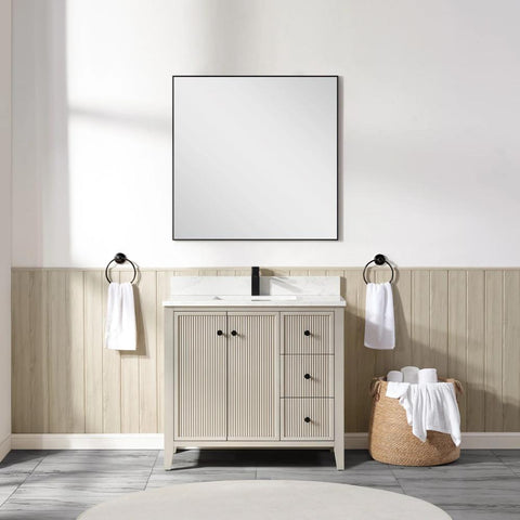 A modern bathroom features a square mirror above a Torino 36 Inch Bathroom Vanity Cabinet with Drawers, black faucet, two towel rings with white towels, and a wicker basket holding rolled towels on a tiled floor.