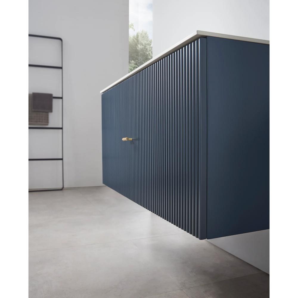 A modern Barcelona 42 Inch Wall Mount Bathroom Vanity in blue with vertical grooves and a gold handle, set against a light gray tiled floor and white wall, with towels on a black rack in the background.