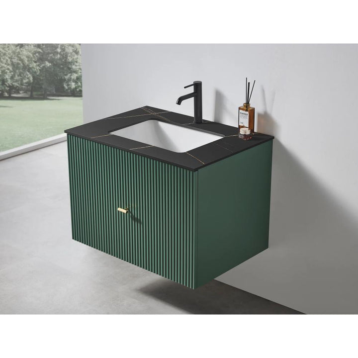 The Barcelona 30 Inch Wall Mount Bathroom Vanity showcases a dark green ribbed front, black integrated sink and countertop, matte black faucet, and gold handle. A diffuser rests atop the vanity, while a window provides a view of greenery.