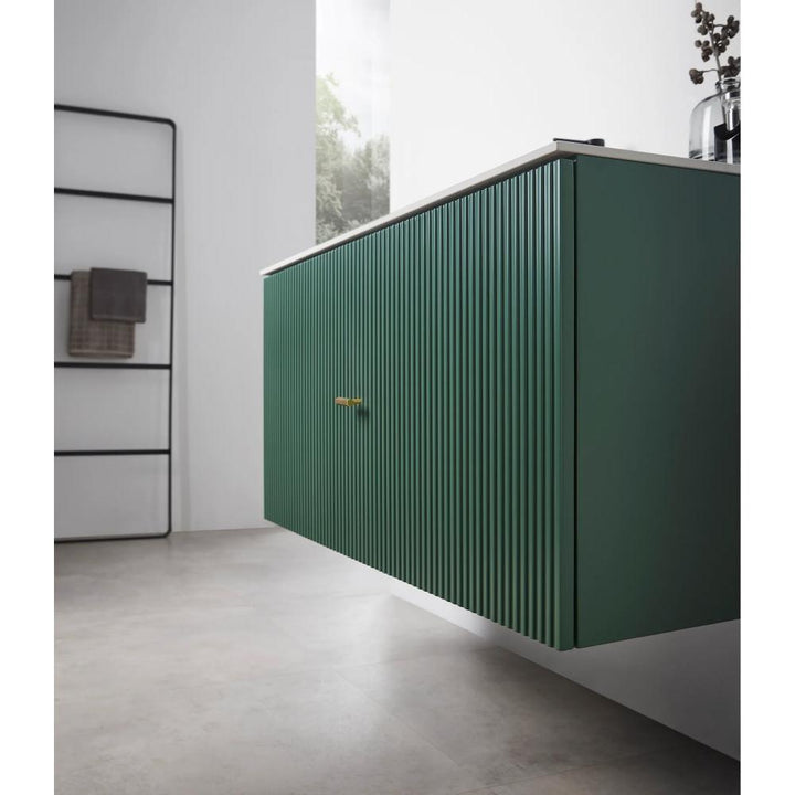 A modern bathroom features the Barcelona 42 Inch Wall Mount Bathroom Vanity in green with vertical grooves, a white countertop, and a single brass handle. In the background, a black towel rack holds neatly folded towels.