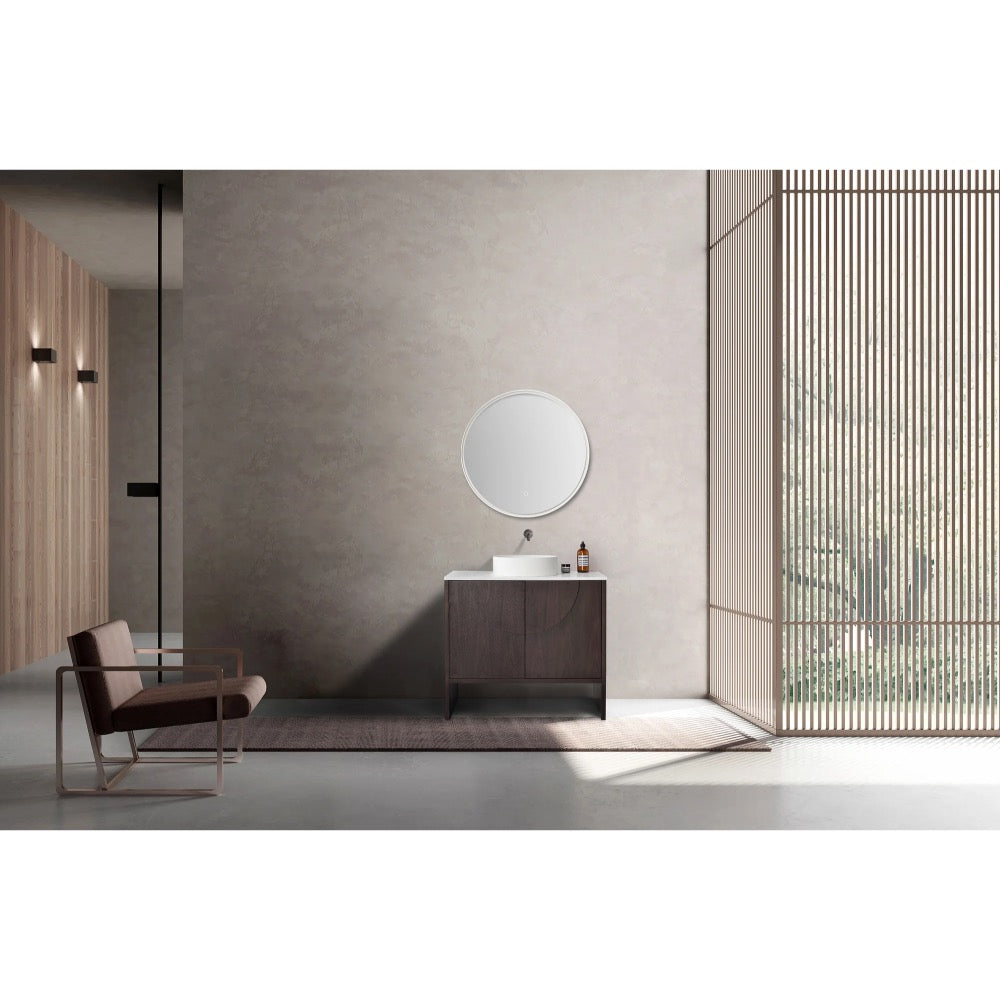 Minimalist bathroom featuring the Celle 36 Inch Bathroom Vanity With Vessel Sink topped with a round mirror, a modern chair on the left, and a large window with vertical wooden slats letting in natural light.