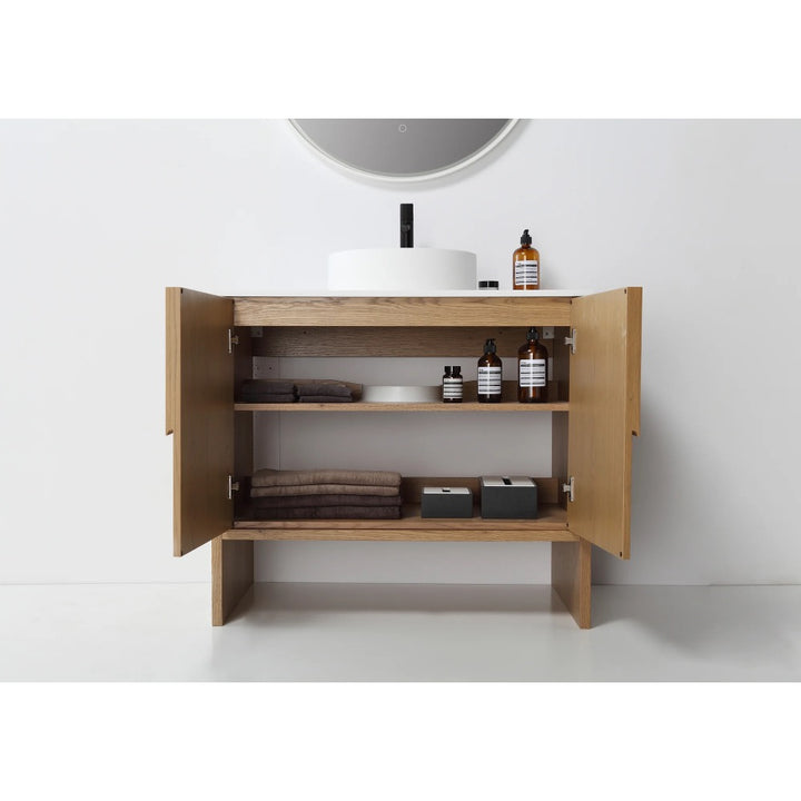The Celle 36 Inch Bathroom Vanity With Vessel Sink has open doors displaying shelves with folded towels, toiletries, bottles, and storage boxes under a round sink and mirror on a white wall.