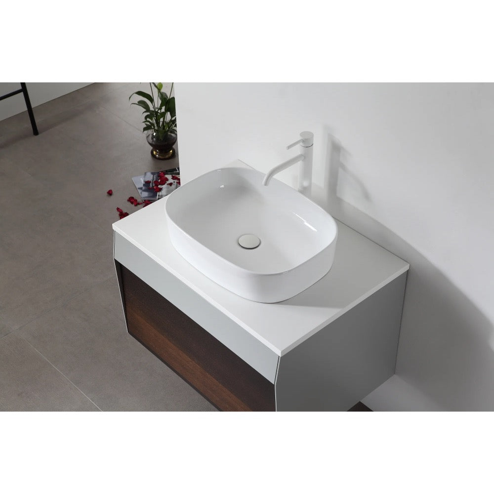 A modern white rectangular vessel sink with matching faucet sits atop the Ronda 30 Inch Wall Mount Bathroom Vanity, set against a pristine white wall. Nearby, a small plant and scattered red flower petals add a touch of elegance.