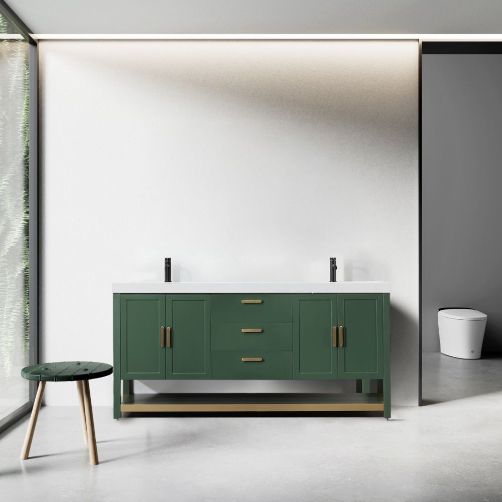 A modern bathroom showcases the Winchester 72 Forest Green Vanity with a white countertop and brass handles, flanked by two faucets. A round green stool with wooden legs is on the left by a large window, while a white toilet is secluded on the right behind a partial wall.