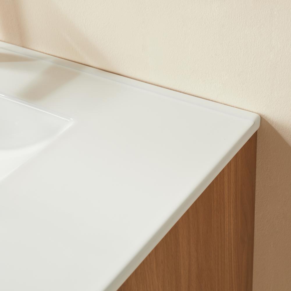 Close-up of a bathroom countertop with a smooth white surface and wooden cabinet base against a pale beige wall, featuring the sleek Linea 36 Inch Wall Mounted Bathroom Vanity. A portion of the built-in sink is visible on the left.