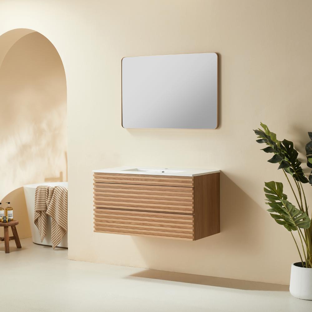 Minimalist bathroom with a Linea 36 Inch Wall Mounted Bathroom Vanity, rectangular mirror above, potted green plant on the right, and a glimpse of towels and bath items near an arched doorway in a beige-toned room.