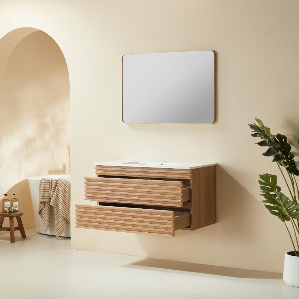 Minimalist bathroom with a Linea 36 Inch Wall Mounted Bathroom Vanity featuring two open drawers, a rectangular mirror above, a potted plant on the floor, and a bathtub in the background with folded towels on a stool.