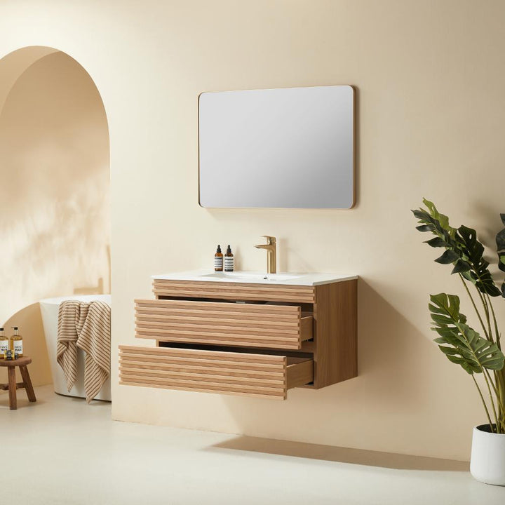 Minimalist bathroom with a Linea 36 Inch Wall Mounted Bathroom Vanity, three open drawers, a square mirror above the sink, potted floor plant, soft neutral decor, arched doorway, and a towel on a stool in the background.