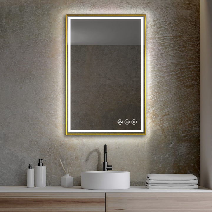 A contemporary bathroom features the Stellar 18 Inch LED Light Bathroom Mirror, framed in gold and mounted on a textured wall. Below, a round white sink with a black faucet is beautifully accented by soap dispensers, a reed diffuser, and neatly stacked towels.