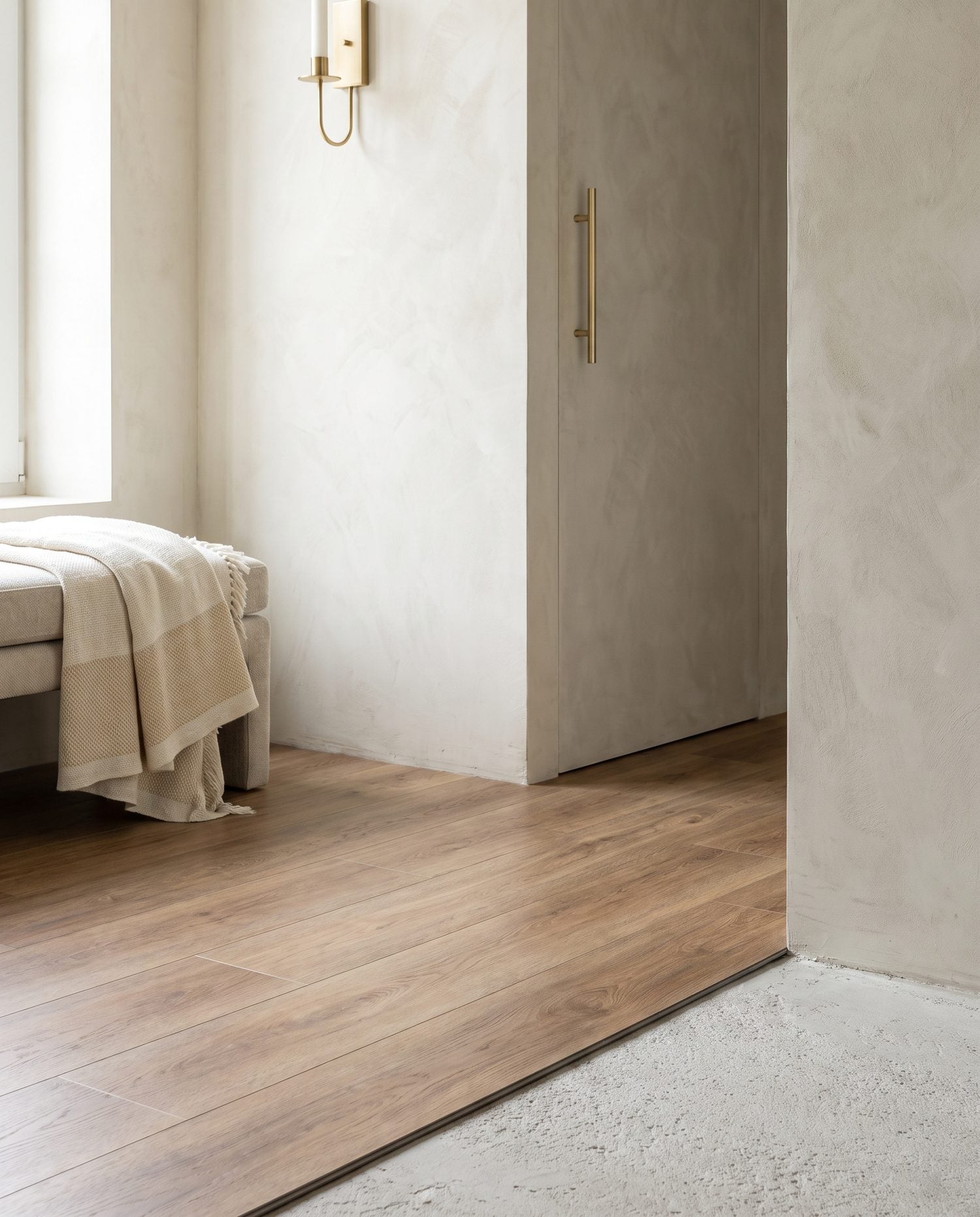 Close-up of warm wood-look LVT plank flooring laid over a concrete subfloor edge in a basement