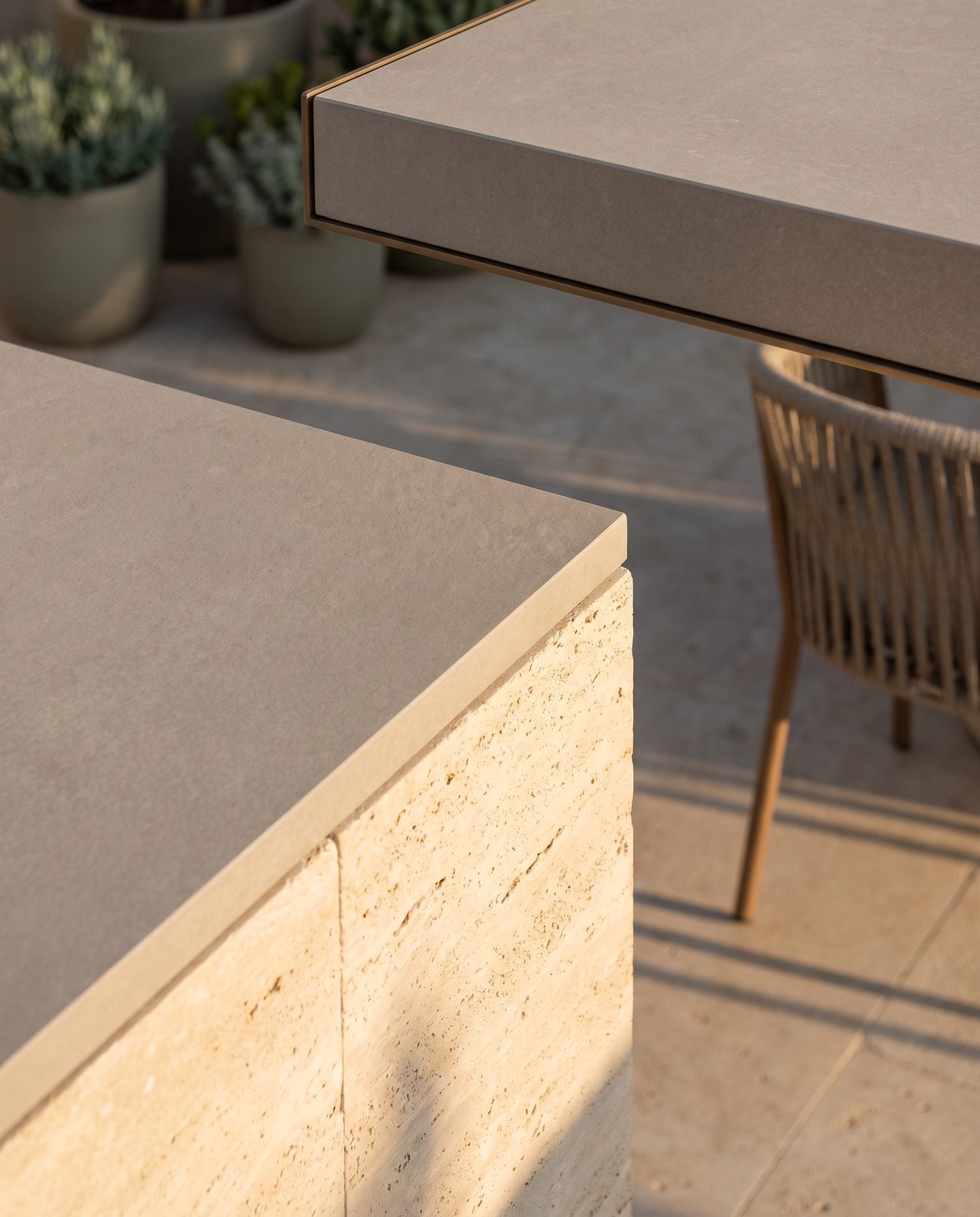 Tight detail of a 2cm porcelain paver edge meeting a natural stone paver border in an outdoor patio, warm daylight