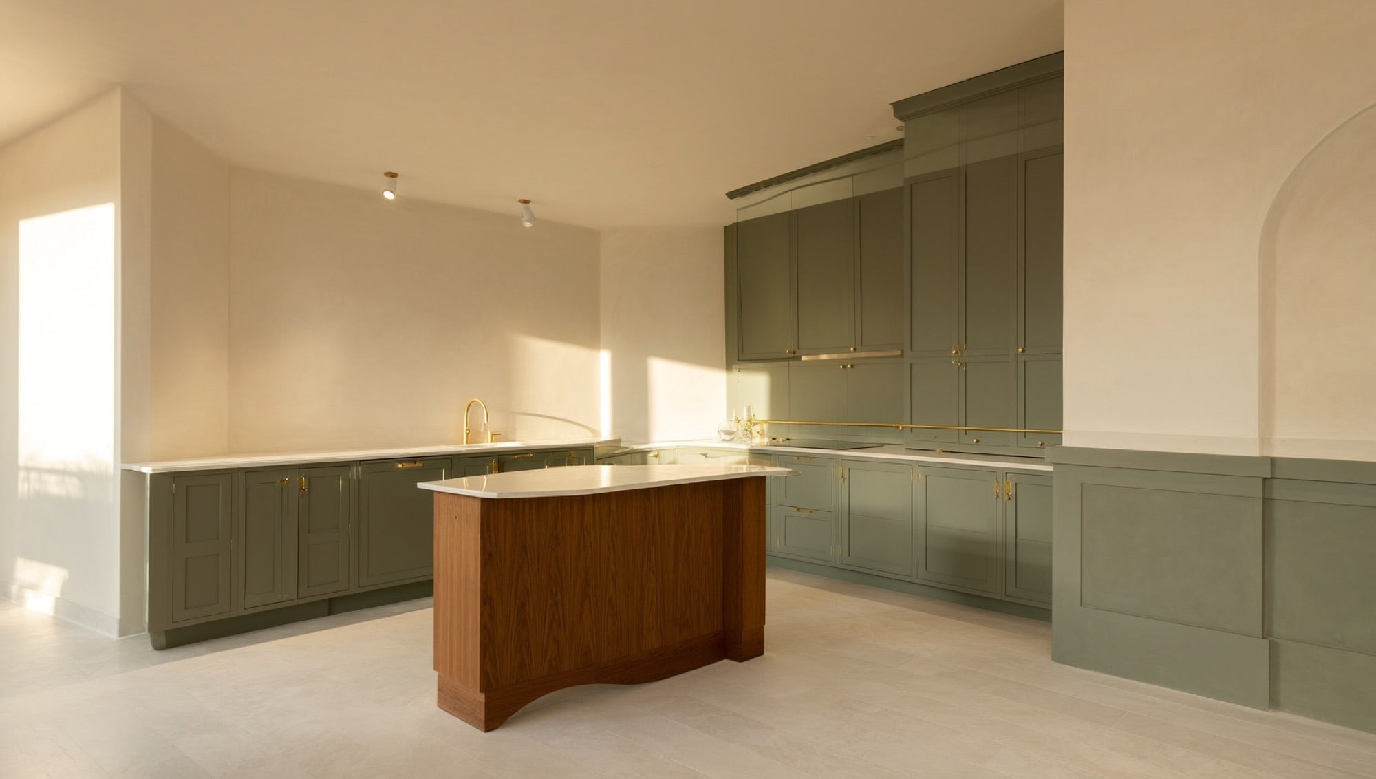 Two-tone kitchen with sage green cabinetry and walnut island with brass pulls