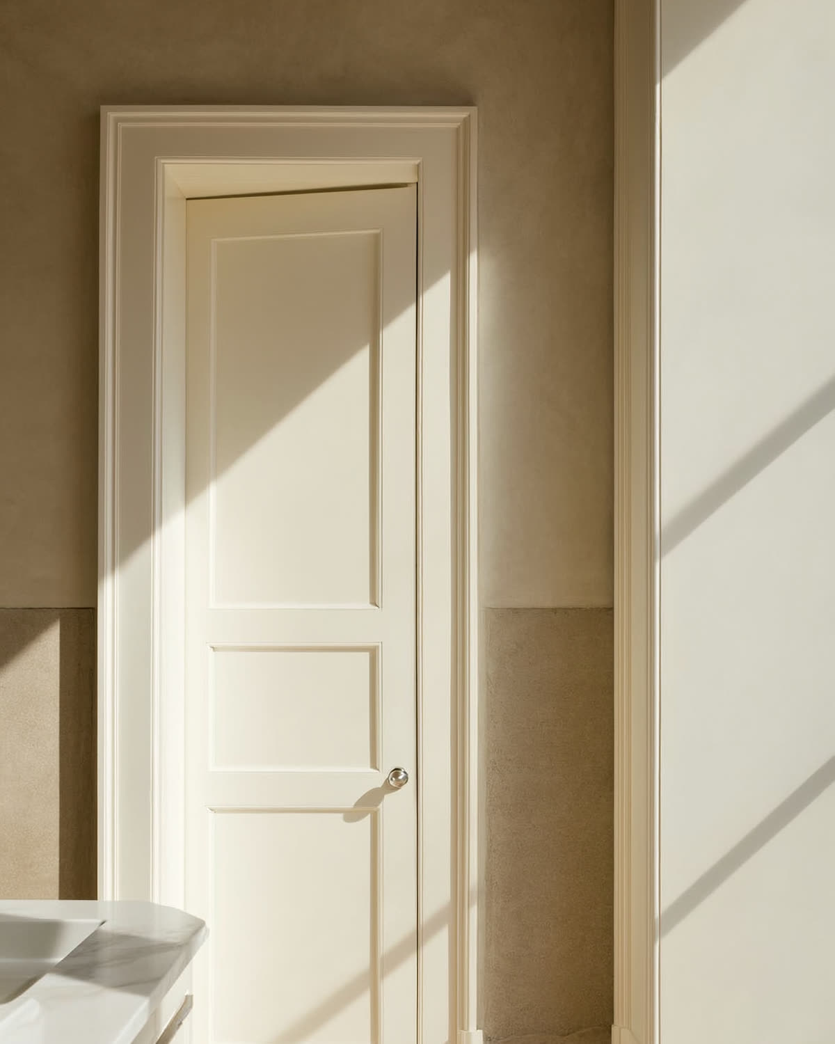 White paneled door with nickel knob beside a marble countertop edge