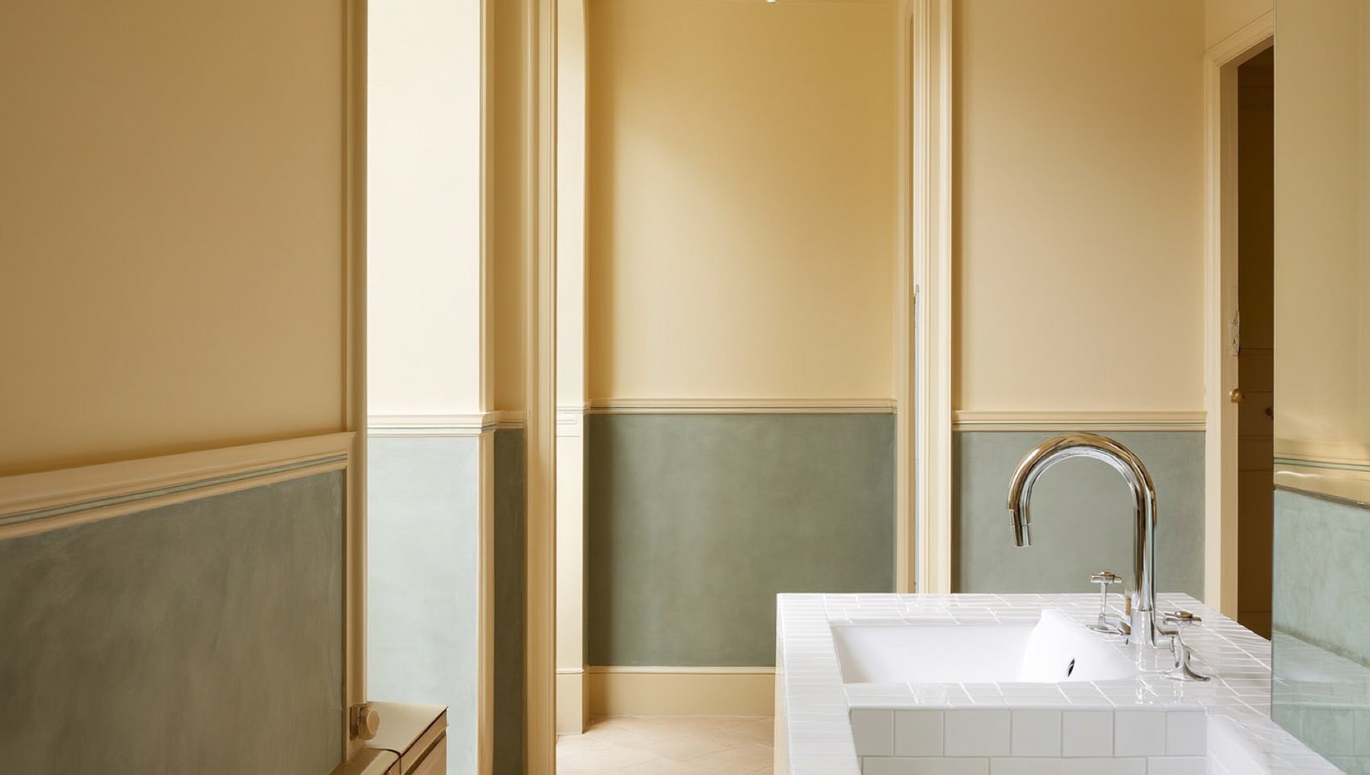 Polished chrome faucet on white fireclay sink with subway tile