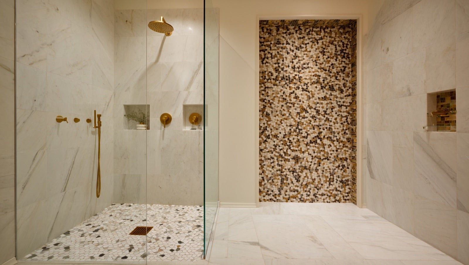 Walk-in shower combining large-format marble-look walls, mosaic floor and a contrasting tiled niche