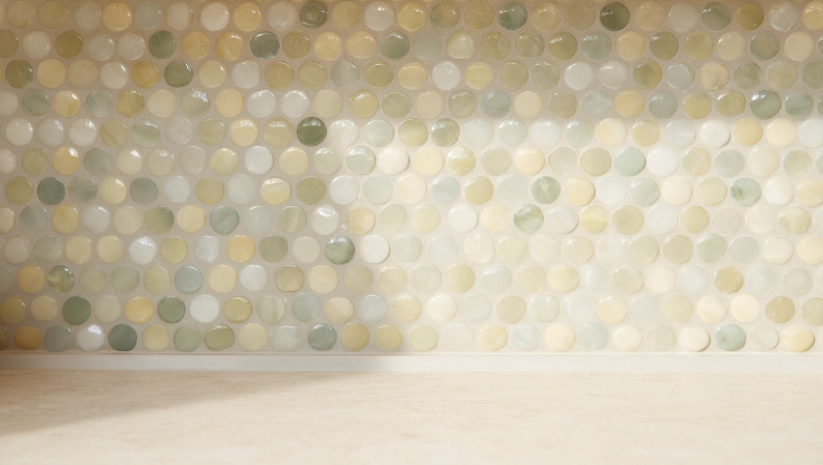 Recycled-glass penny round mosaic backsplash in cream and beige tones with a mix of matte and glossy pieces under warm cabinet lighting.