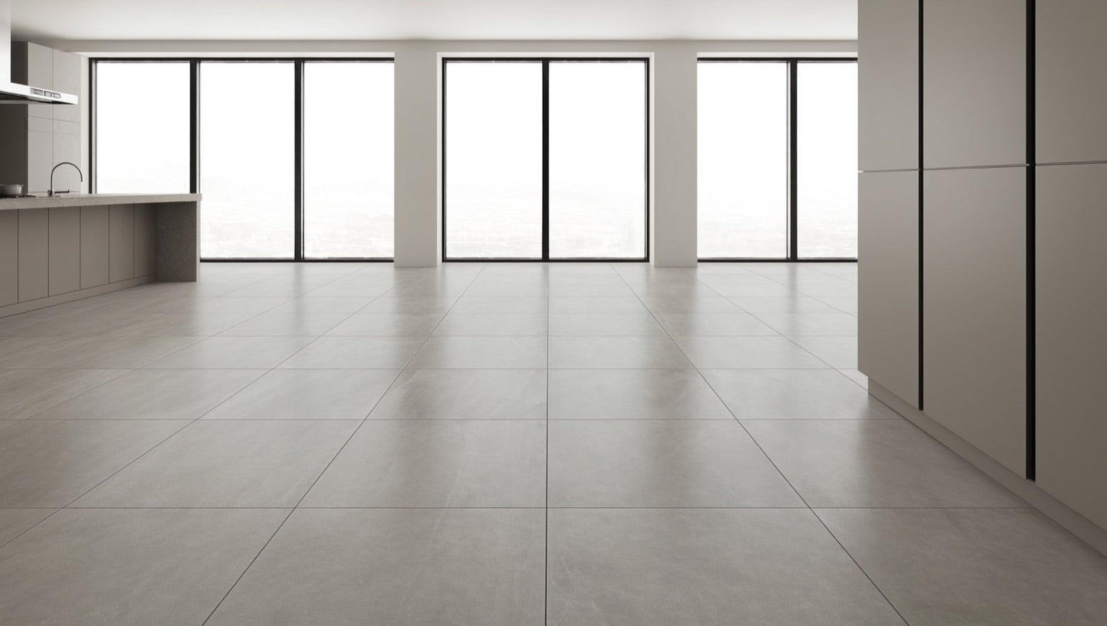 Open-plan kitchen and dining area floored in 32x32 matte stone-look porcelain tile in a soft grey tone, with minimal grout lines running toward large windows