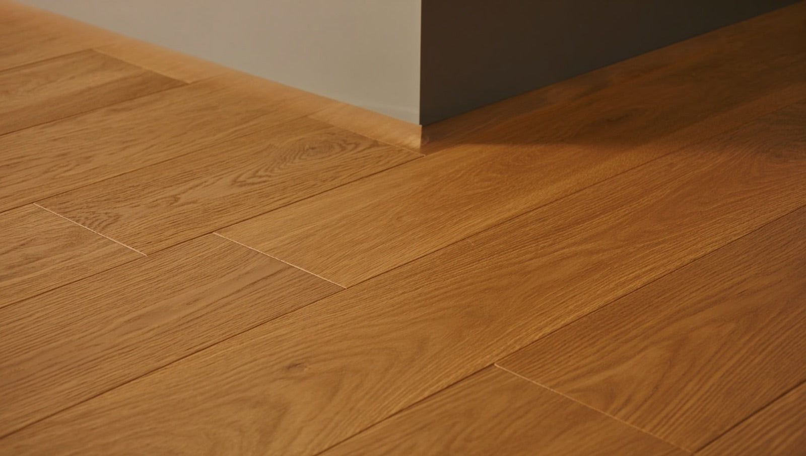 Kitchen floor of 8x48 wood-look matte porcelain planks in warm oak tones with staggered joints, meeting the painted base of a kitchen island