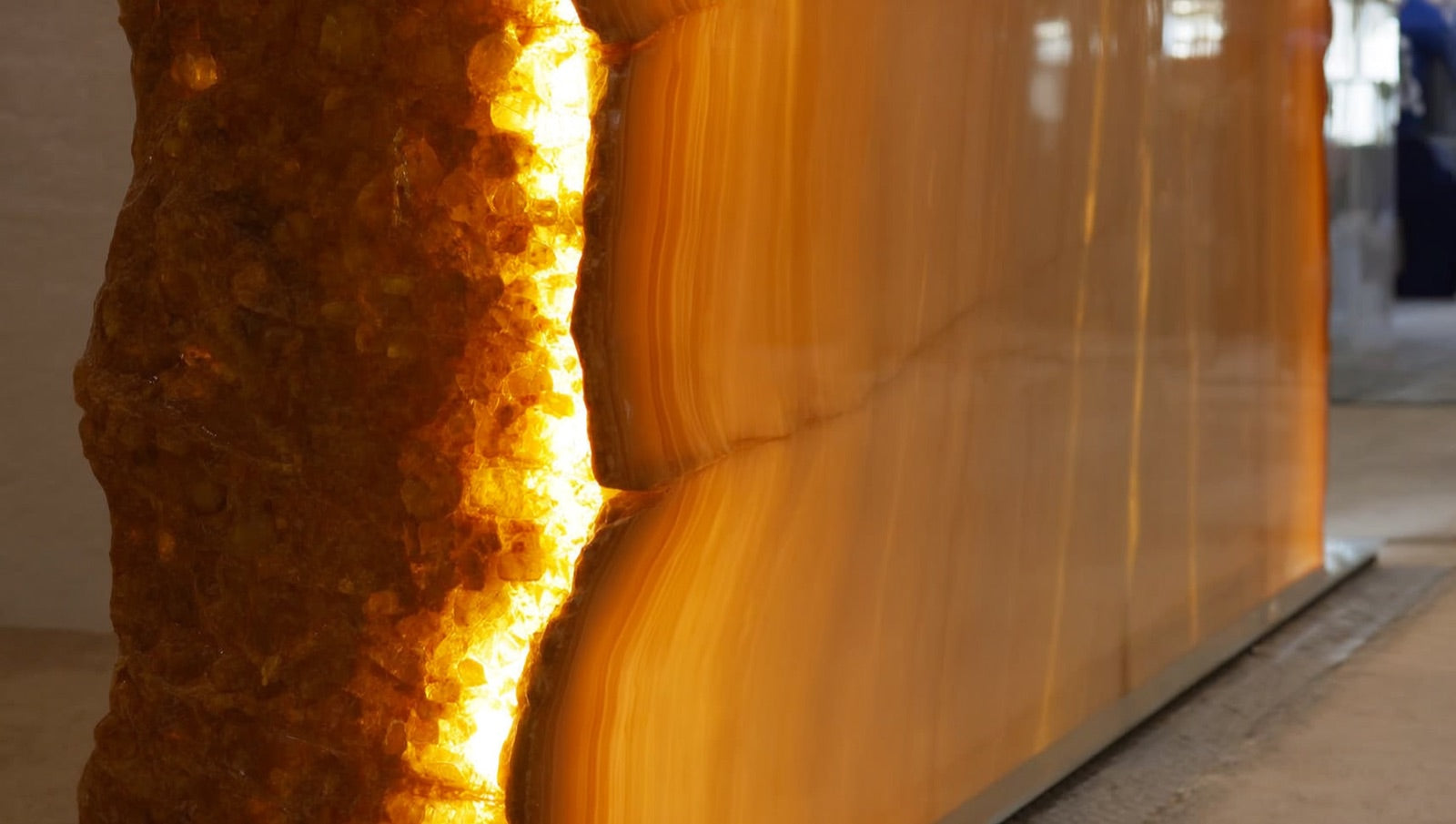 Close detail of a polished porcelain slab with deep amber and gold gemstone-style veining catching warm light, showing continuous crystalline movement across the large-format face.