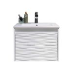 A modern white bathroom vanity with a textured, wavy front panel, a rectangular sink, a black faucet, a soap dispenser, and two bottles on the countertop, set against a plain white background.