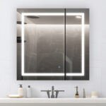 The Royale Plus 30 Inch x 36 Inch LED Lighted Mirror Medicine Cabinet is mounted above a sink with a faucet, soap dispenser, and other toiletries on the countertop.